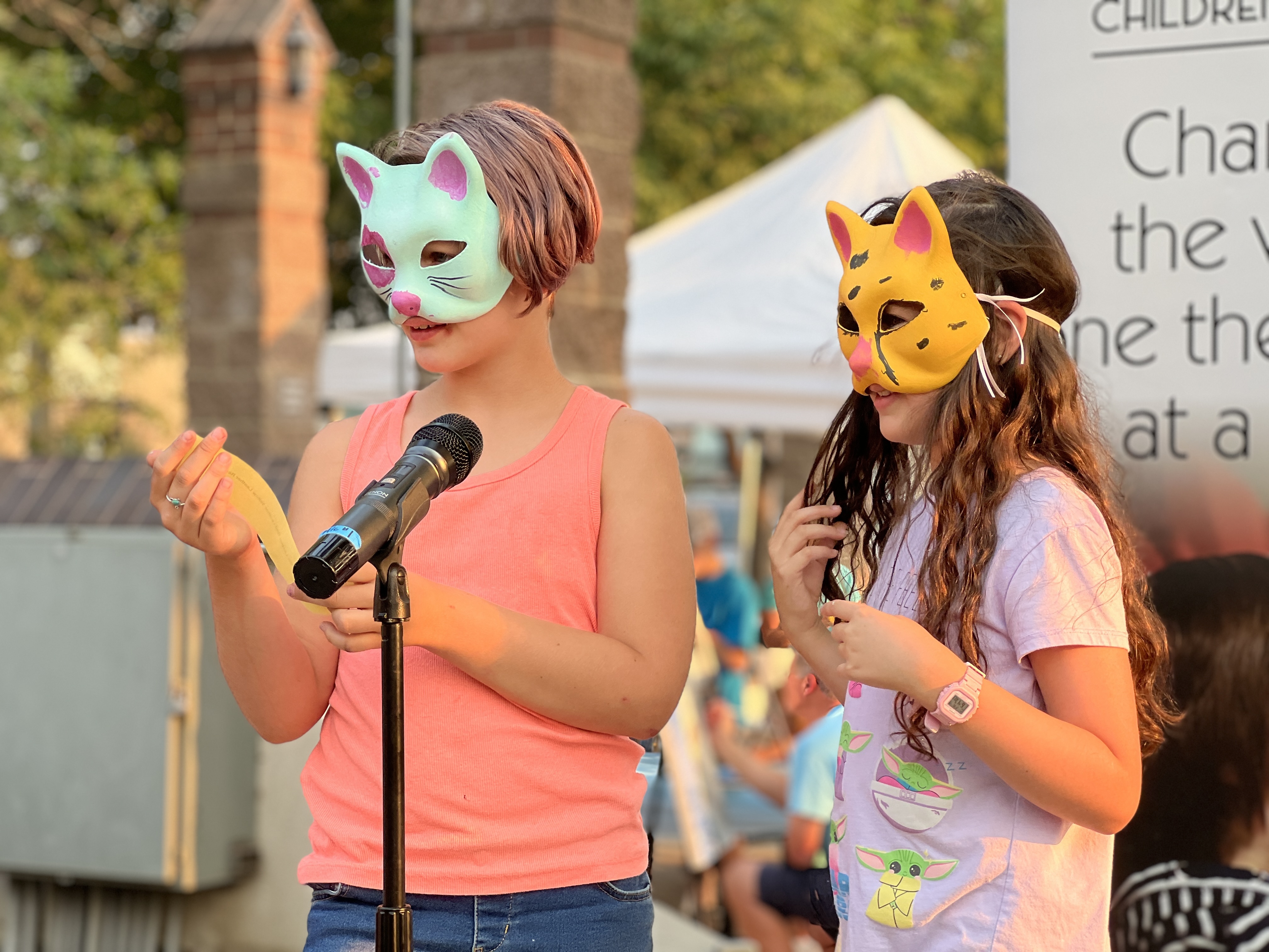 two children wearing handmade mask reading a poem on stage